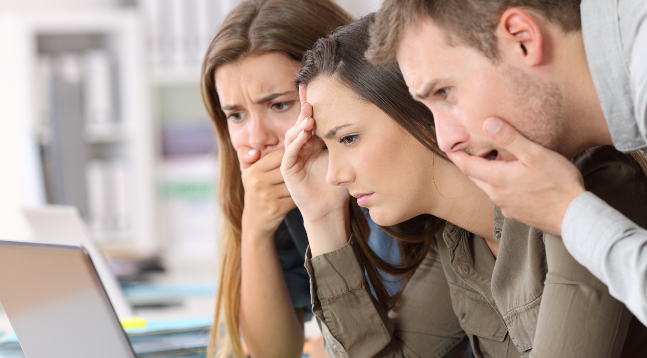 Junge Menschen blicken erschrocken auf Monitor