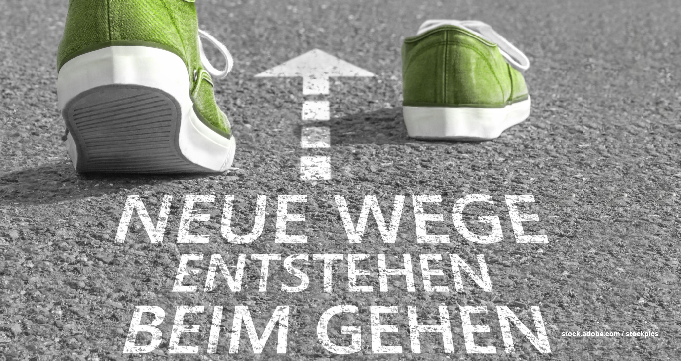 Grüne Sneakers auf einer Straße mit der Aufschrift neue Wege entstehen beim Gehen