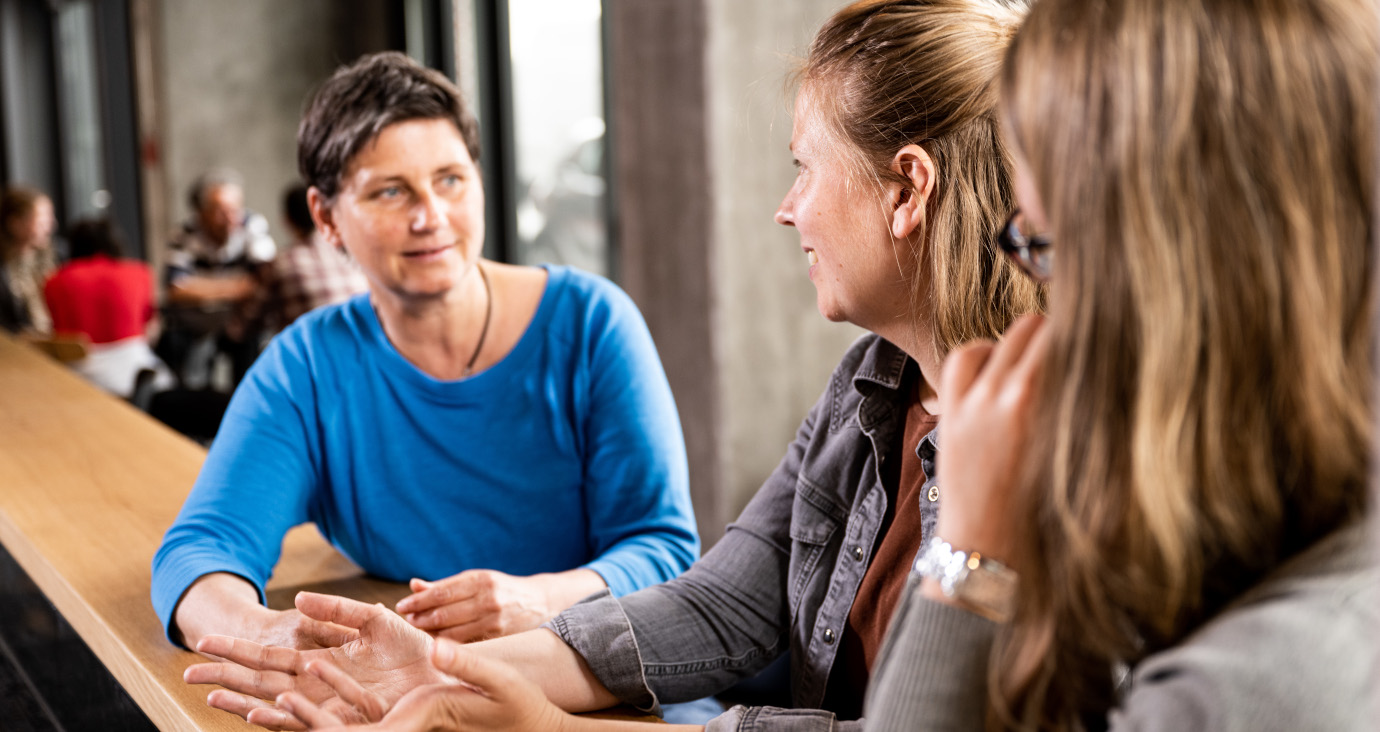 Drei Frauen an einem Tresen, die sich unterhalten